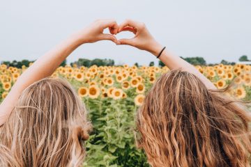 two young people in front of field of sunflowers